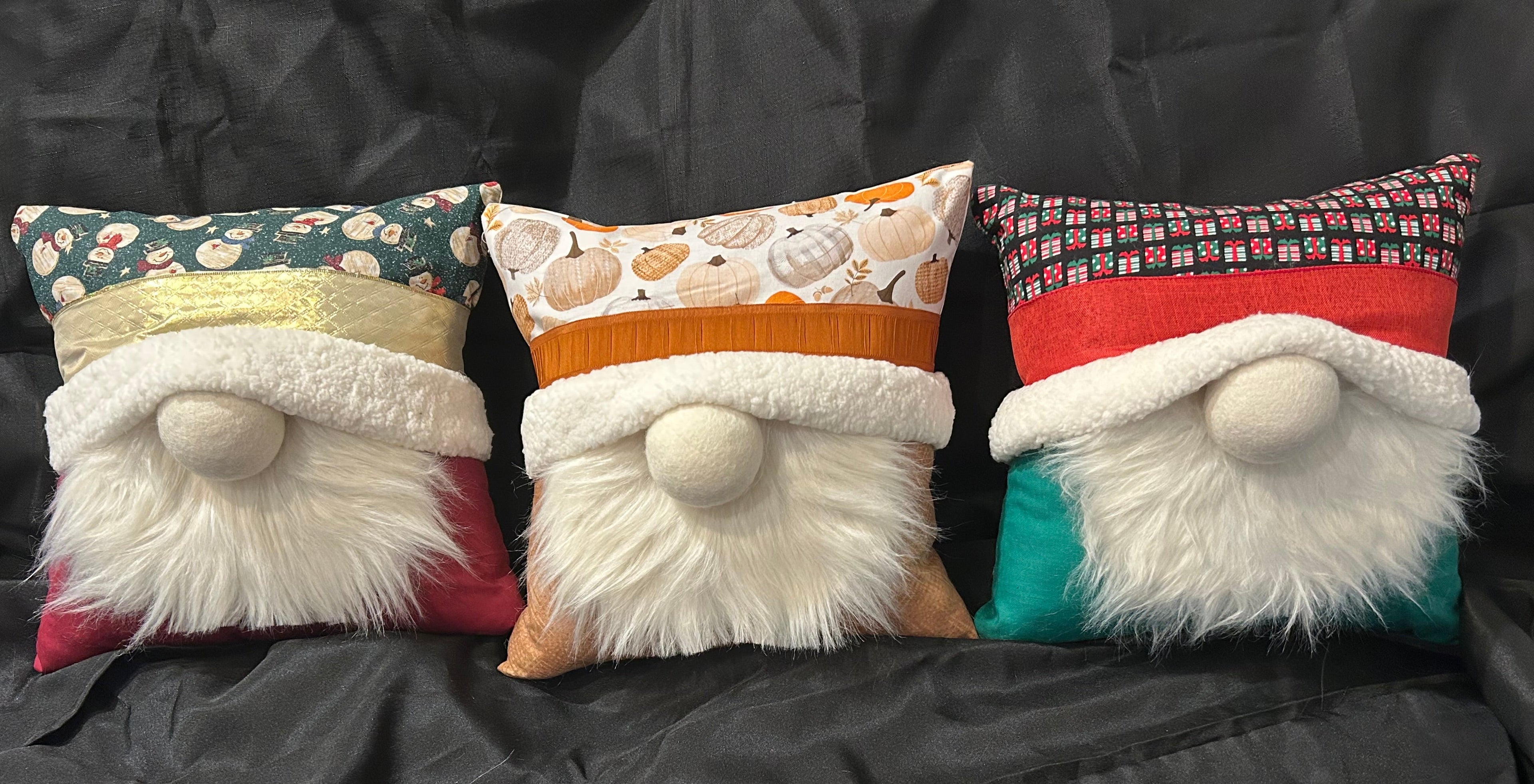 Three gnome-shaped cushions with colorful hats on a dark surface